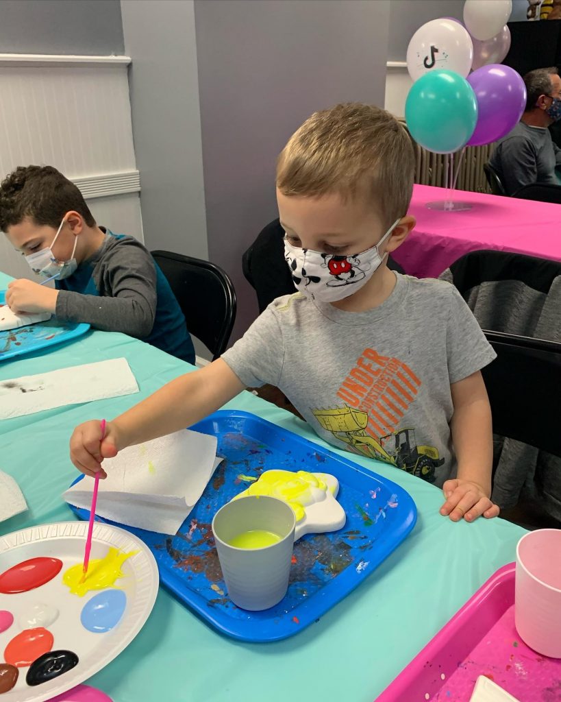 Boy in mask painting during plaster paint party