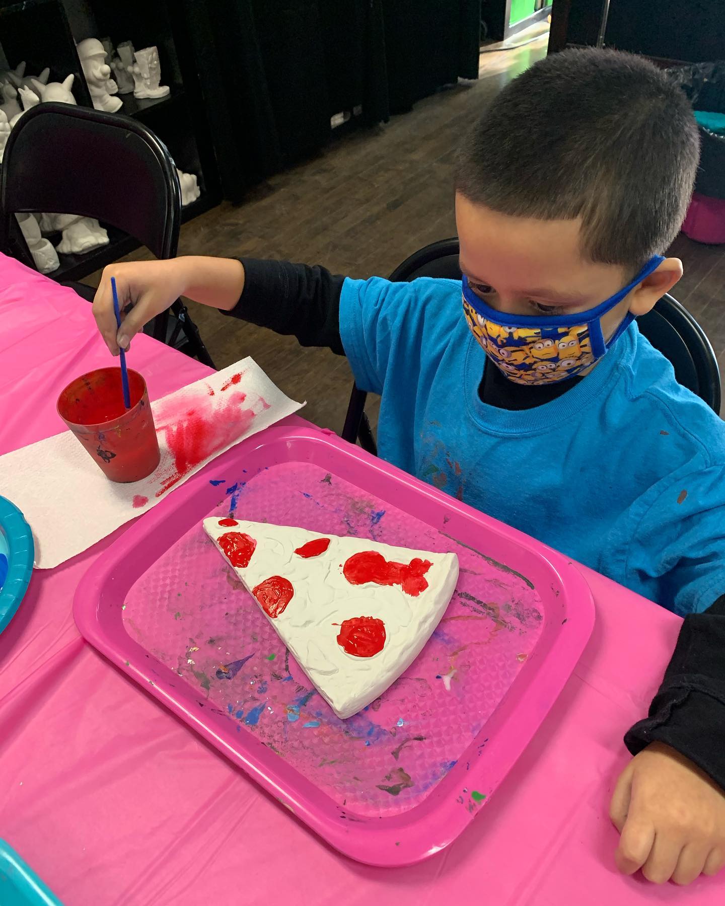 Boy in mask painting pizza plaster piece