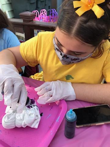 Girl in mask and gloves making tie dye