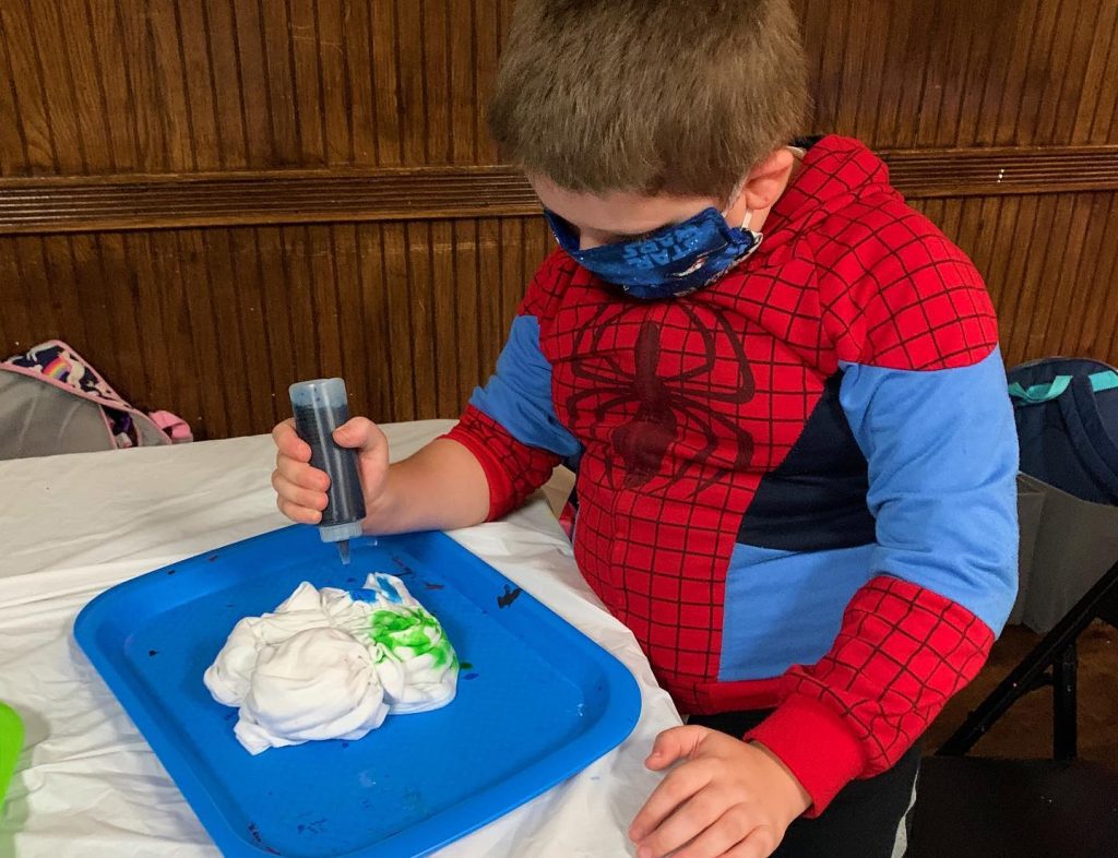 Boy in Spiderman costume making tie dye shirt