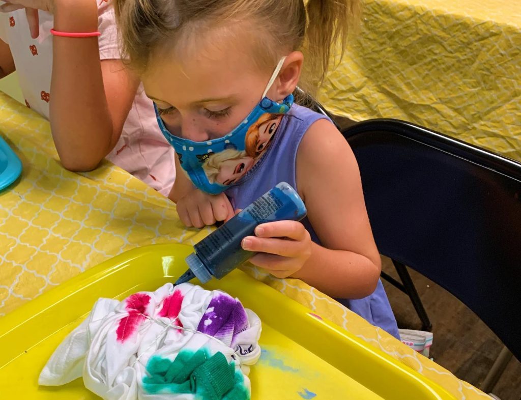 Cute girl in Frozen mask making tie dye