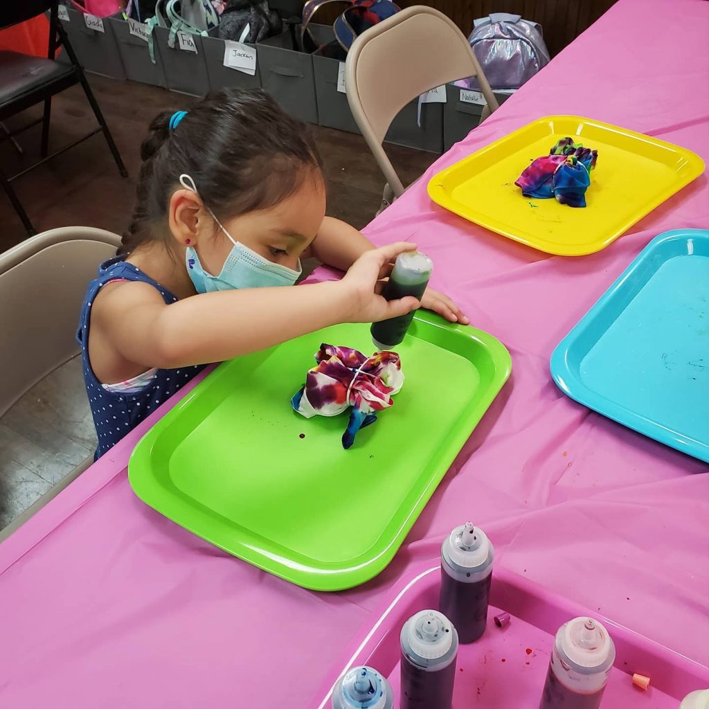 Girl in mask making tie dye shirt