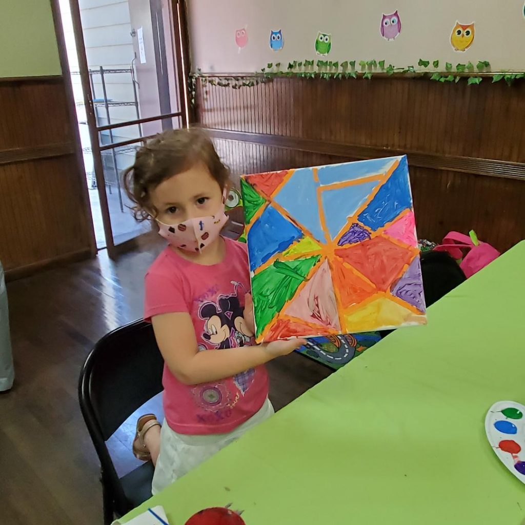 Cute little girl showing mosaic canvas painting